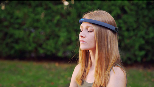 Woman sitting outdoors with her eyes closed, wearing a FocusCalm EEG headband